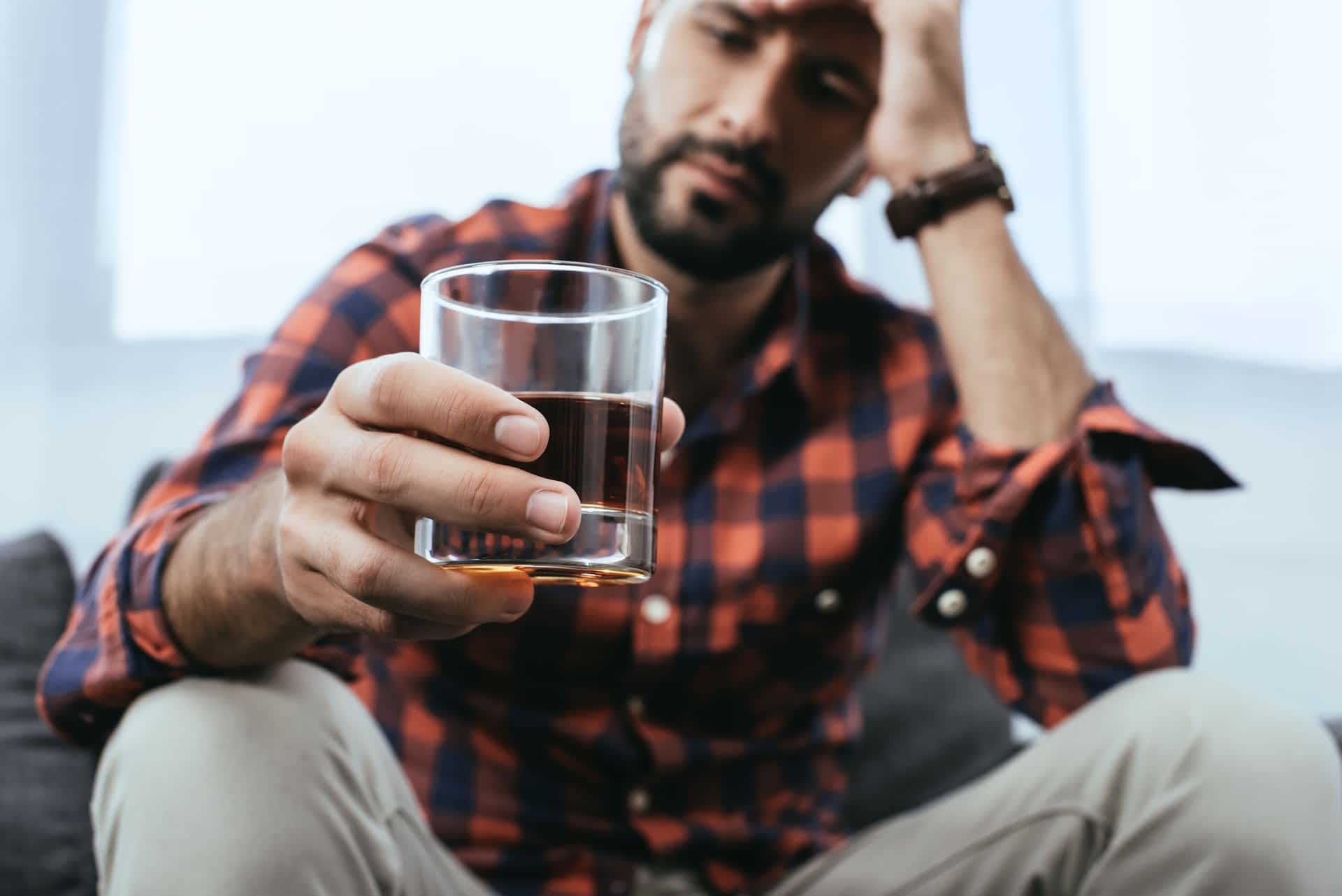 Man looking at a glass of alcohol