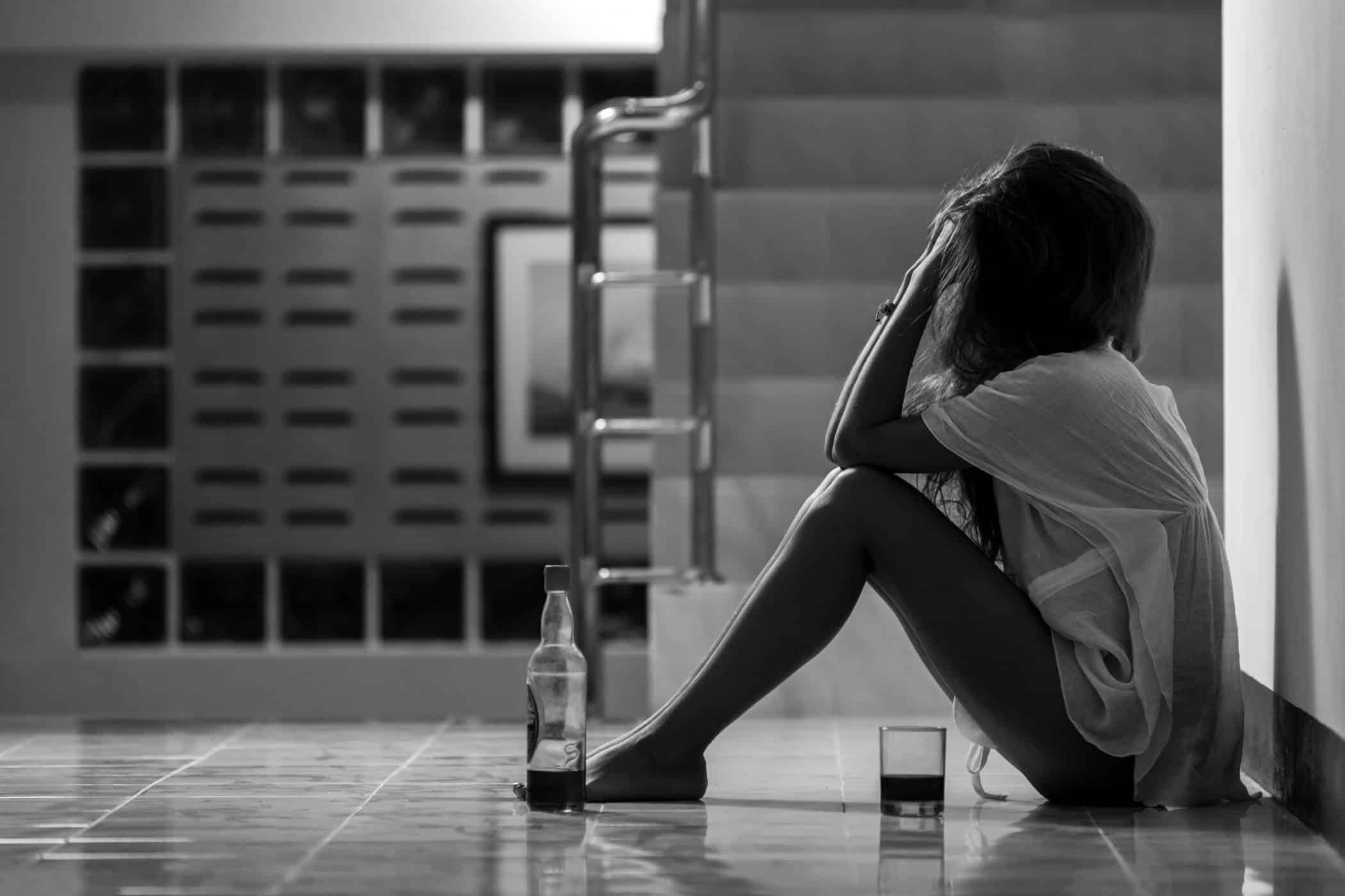 Girl in depression drinking alcohol in solitude